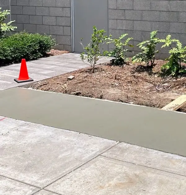 Freshly poured concrete foundation beside the planted bed of the Ascension Parish Memorial Garden, an Eagle Scout project